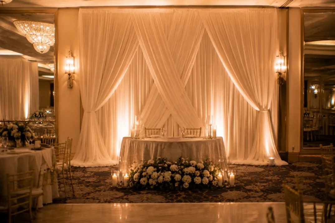 Elegant sweetheart table with a layered fabric wedding backdrop